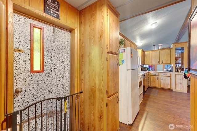 kitchen with freestanding refrigerator, light countertops, lofted ceiling, and wood finished floors