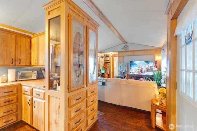 kitchen with vaulted ceiling with beams, a toaster, open floor plan, light countertops, and dark wood-style floors