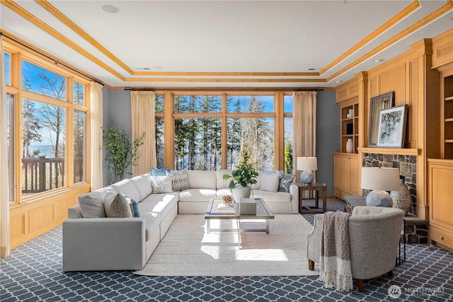 carpeted living area featuring built in features, a raised ceiling, and ornamental molding