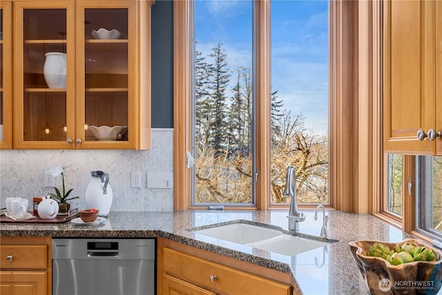 kitchen with light stone counters, tasteful backsplash, glass insert cabinets, a sink, and dishwasher