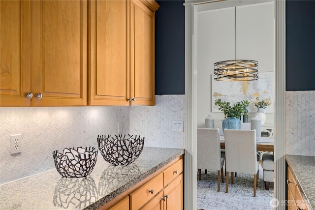 kitchen featuring tasteful backsplash, brown cabinetry, and light stone countertops