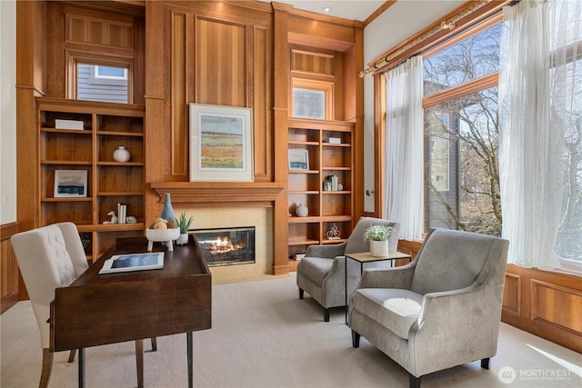 living area with built in shelves, a glass covered fireplace, and light colored carpet