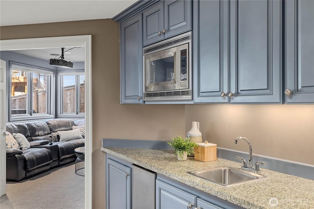 kitchen featuring light countertops, stainless steel microwave, open floor plan, carpet flooring, and a sink