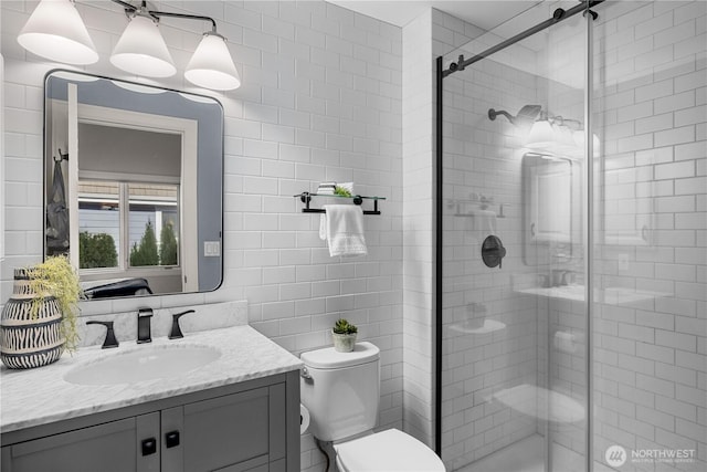 bathroom with toilet, a stall shower, vanity, and tile walls