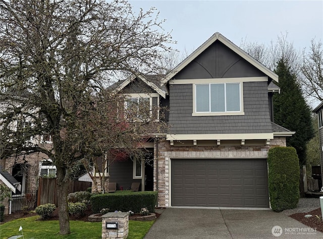 view of front of property with stone siding, driveway, an attached garage, and fence