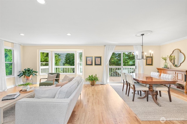 living area with a chandelier, recessed lighting, light wood-style floors, baseboards, and crown molding