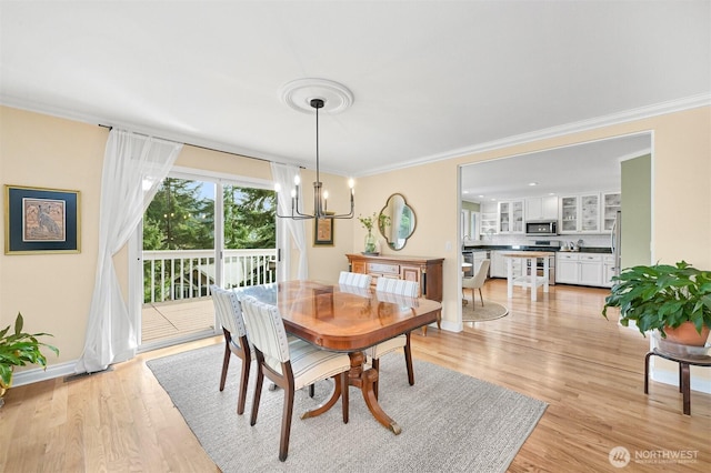 dining room with a chandelier, light wood-type flooring, crown molding, and baseboards