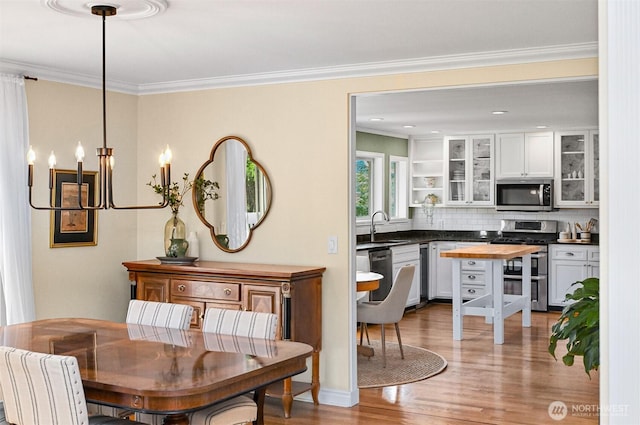 dining room with an inviting chandelier, light wood-style flooring, and ornamental molding