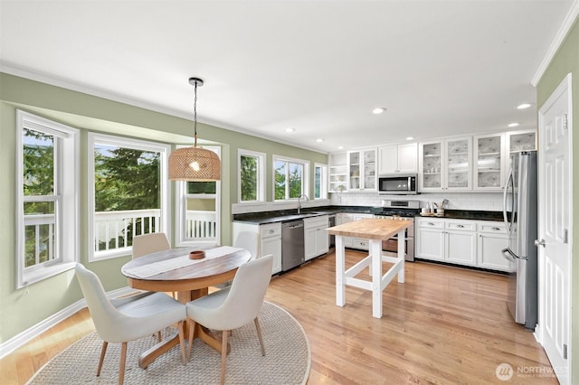 kitchen with stainless steel appliances, white cabinetry, backsplash, light wood finished floors, and dark countertops