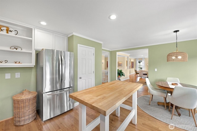 kitchen featuring light wood finished floors, white cabinetry, ornamental molding, and freestanding refrigerator