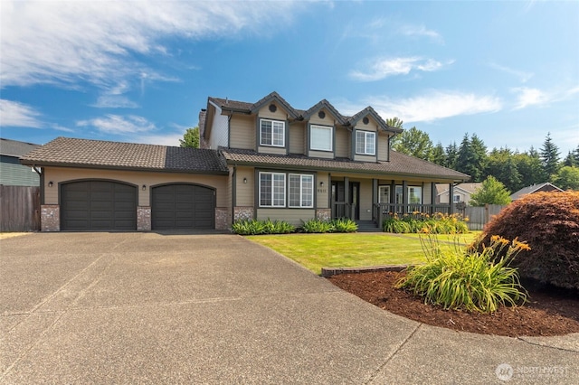 view of front facade with an attached garage, fence, driveway, a tiled roof, and a front lawn