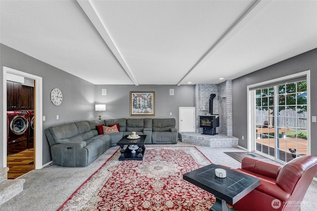 living area with beamed ceiling, independent washer and dryer, a wood stove, carpet, and a textured ceiling