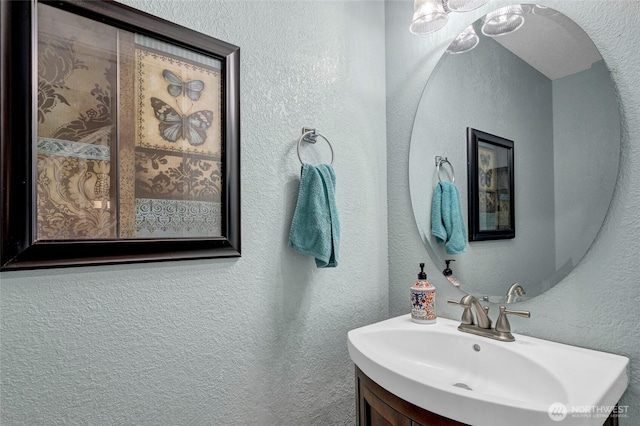 bathroom with a textured wall and vanity