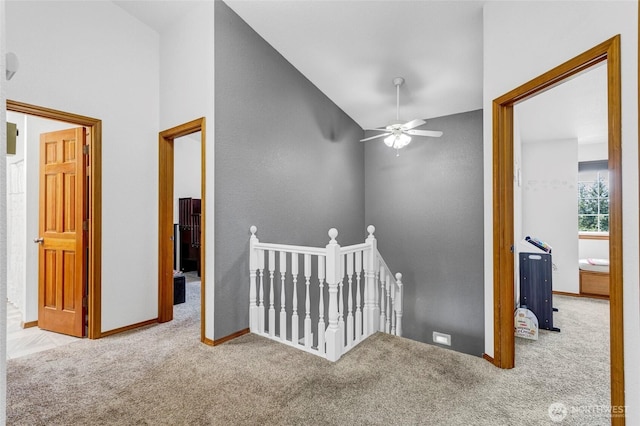 hall featuring carpet floors, baseboards, vaulted ceiling, and an upstairs landing