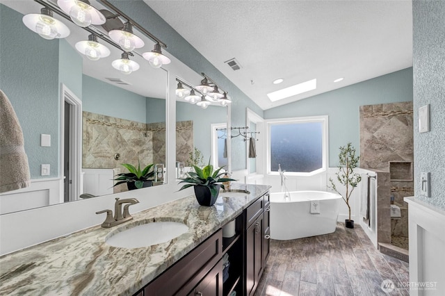 full bathroom featuring lofted ceiling with skylight, a stall shower, a sink, and wood finished floors