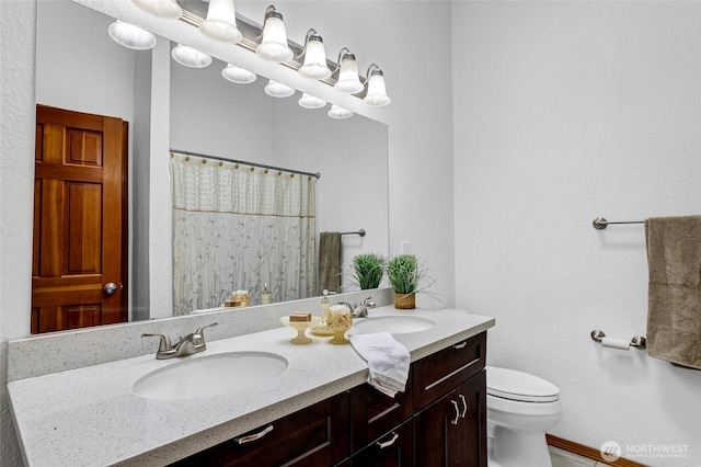 bathroom featuring a shower with curtain, a sink, toilet, and double vanity