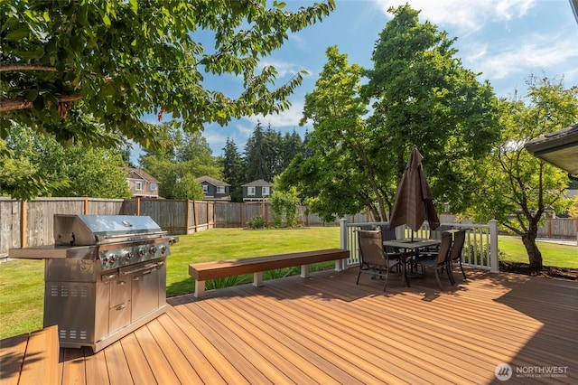 wooden deck featuring outdoor dining space, a fenced backyard, a lawn, and grilling area