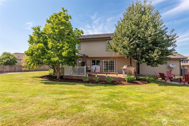 rear view of property with a yard, fence, and a deck