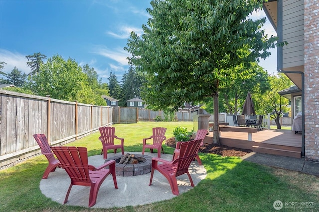 view of yard with a fenced backyard, a fire pit, and a deck