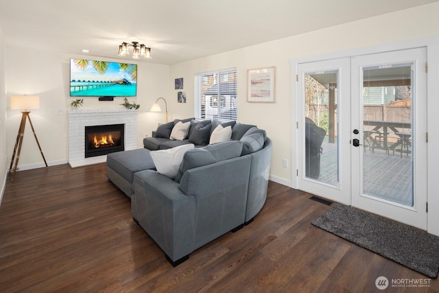 living room with visible vents, baseboards, french doors, a brick fireplace, and dark wood-style floors