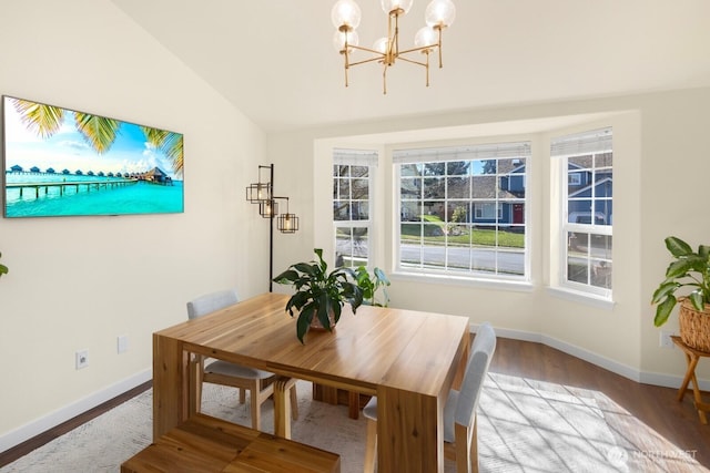 dining area featuring lofted ceiling, baseboards, a chandelier, and wood finished floors