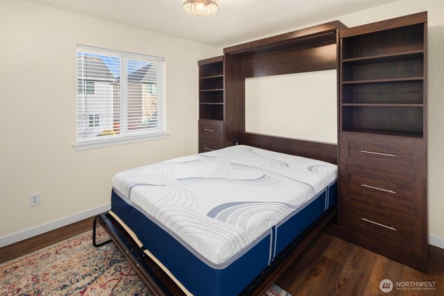 bedroom featuring baseboards and dark wood-style flooring