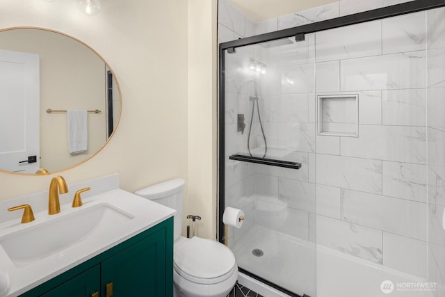 bathroom featuring vanity, a shower stall, and toilet