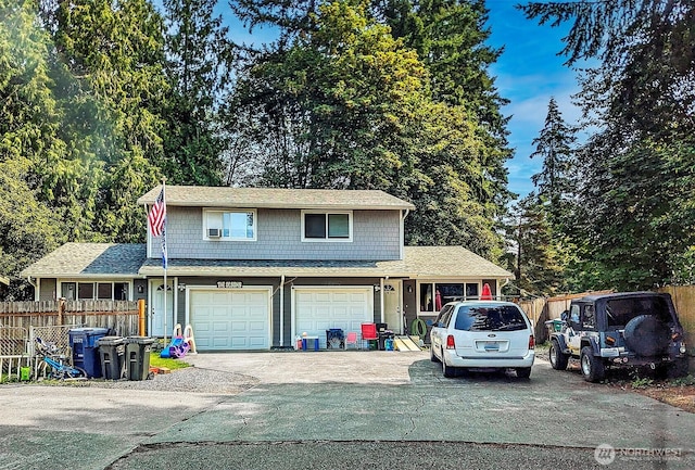 traditional-style home featuring a garage, fence, and concrete driveway