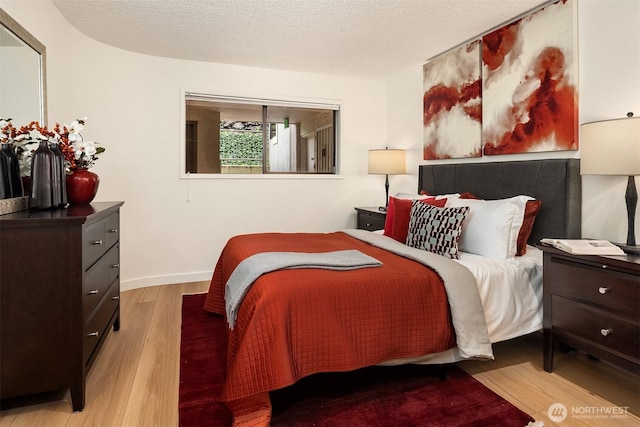 bedroom featuring wood finished floors, baseboards, and a textured ceiling