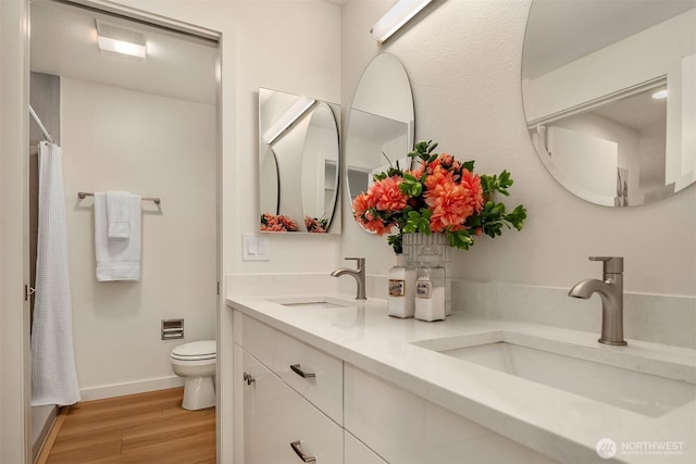 full bathroom featuring a sink, baseboards, toilet, and wood finished floors