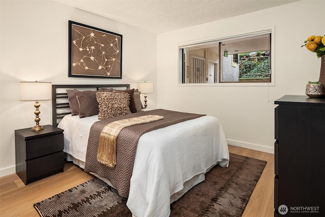 bedroom featuring wood finished floors, baseboards, and a textured ceiling