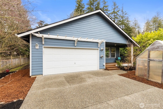 exterior space featuring a greenhouse, an outbuilding, concrete driveway, and fence