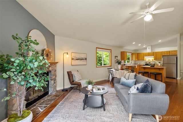 living area with baseboards, lofted ceiling, recessed lighting, a fireplace, and wood finished floors