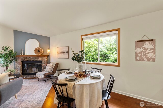 dining space with wood finished floors, a fireplace, and baseboards