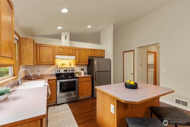 kitchen with visible vents, under cabinet range hood, a sink, washer / clothes dryer, and stainless steel appliances