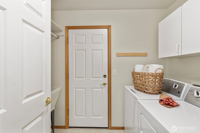 washroom featuring baseboards, cabinet space, and washing machine and dryer