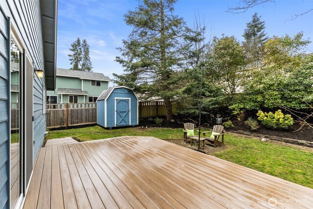 wooden terrace with a lawn, a storage shed, an outdoor structure, and fence