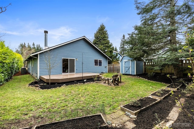 rear view of house with fence, a shed, central AC, a deck, and a garden