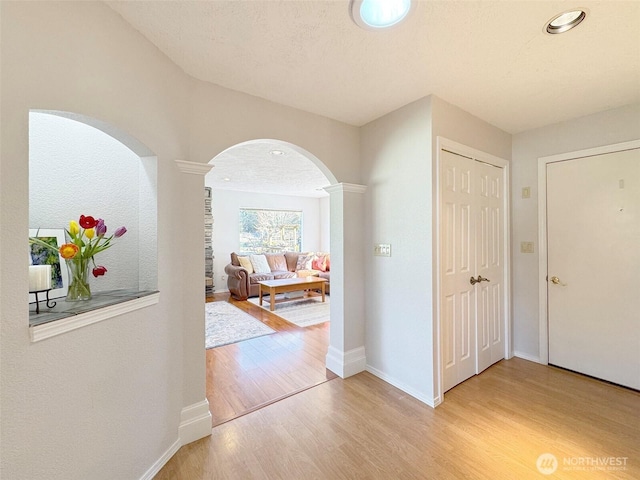 hallway featuring a textured ceiling, baseboards, wood finished floors, and recessed lighting