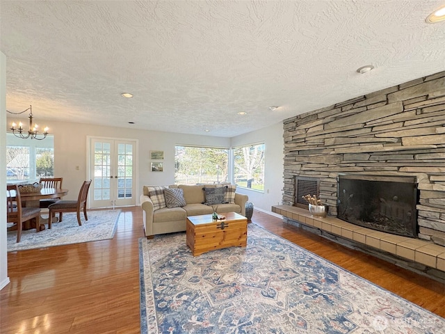 living area with a notable chandelier, a fireplace, baseboards, and wood finished floors