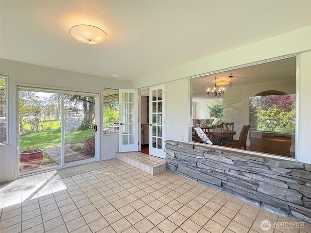 unfurnished sunroom featuring a notable chandelier and french doors