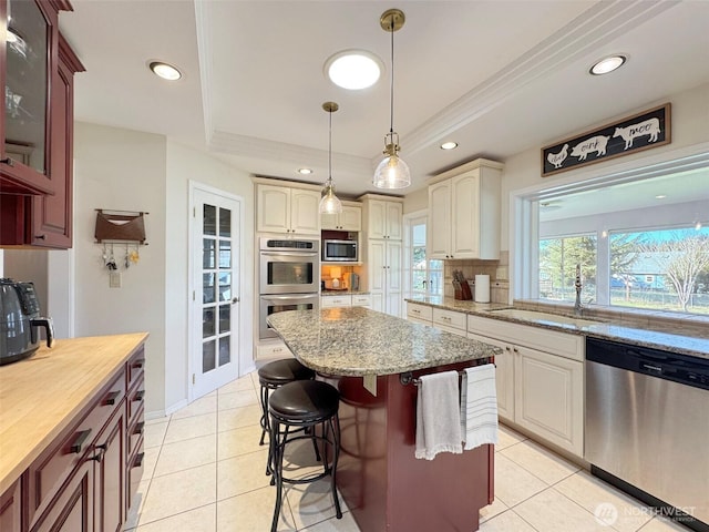 kitchen featuring light tile patterned floors, a sink, appliances with stainless steel finishes, backsplash, and a raised ceiling