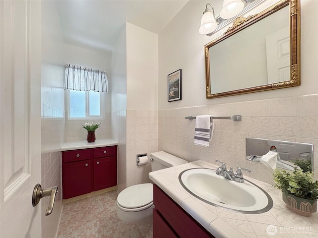 bathroom with wainscoting, tile walls, toilet, and vanity