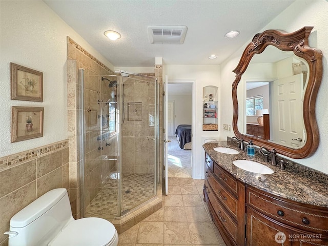 ensuite bathroom with toilet, a shower stall, visible vents, and a sink