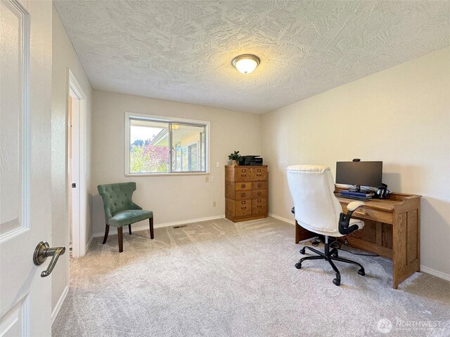 carpeted office with baseboards and a textured ceiling