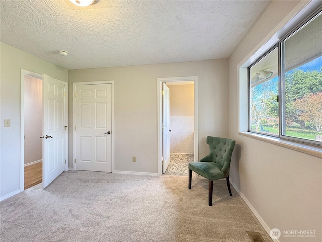 living area with baseboards, a textured ceiling, visible vents, and carpet flooring