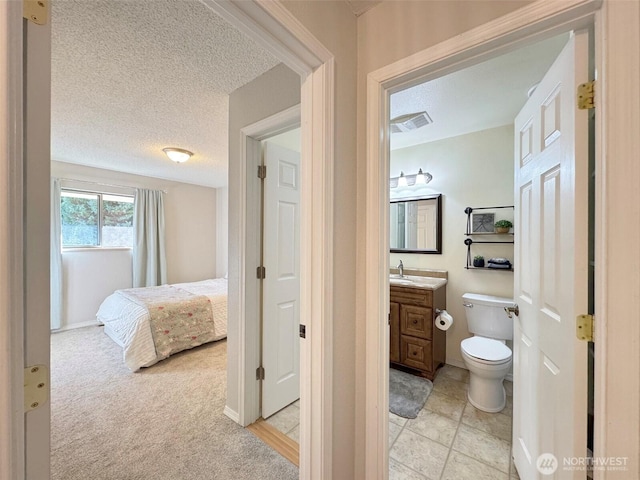 bathroom featuring toilet, visible vents, a textured ceiling, and vanity