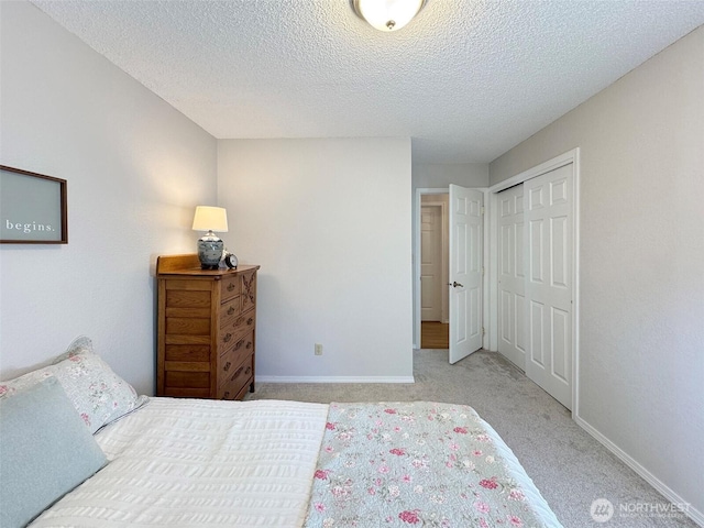 carpeted bedroom with a textured ceiling, baseboards, and a closet