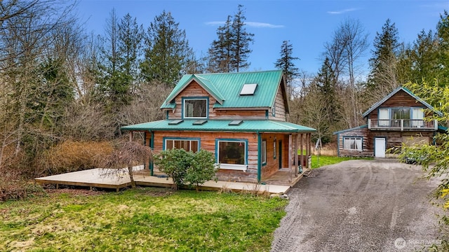 chalet / cabin with a porch, driveway, metal roof, and a front yard