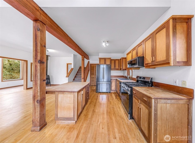 kitchen with a sink, a center island, stainless steel appliances, brown cabinetry, and light wood finished floors